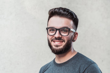 Obraz premium Portrait of a handsome young man standing against gray background. Youth culture. Barbershop.