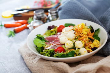 Salad with fusilli pasta accompanied tomatoes, mozzarella, smoked ham and italian cheese