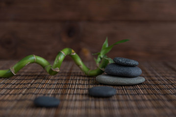Pyramids of gray zen pebble meditation stones with green bamboo leaves and on wooden background. Concept of harmony, balance and meditation, spa, massage, relax