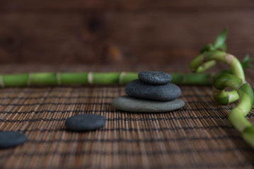 Pyramids of gray zen pebble meditation stones with green bamboo leaves and on wooden background. Concept of harmony, balance and meditation, spa, massage, relax