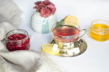 Cold tea with viburnum, honey and lemon on a white fey in a rustic style