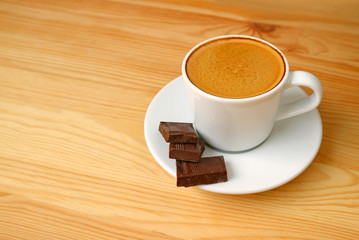 Hot Espresso Coffee and Dark Chocolate Cubes Served on Wooden Table with Free Space for Text and Design 
