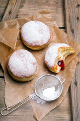Tradycyjne pączki z cukrem pudrem i nadzieniem na drewnianym tle. Smaczne pączki z dżemem  © czarny_bez