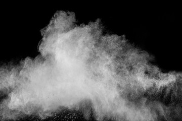 Freeze motion of white dust particles on black background. White powder explosion.