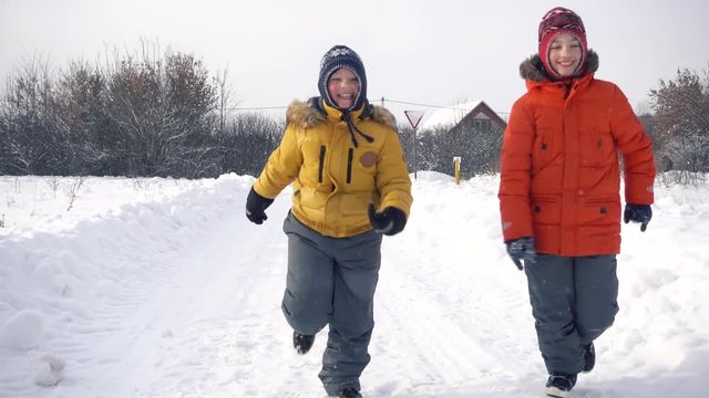 Happy childs runs through a snowy  during a snowfall . Slow motion