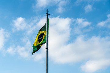 Brazilian Flag Waving Against a blue sky background.