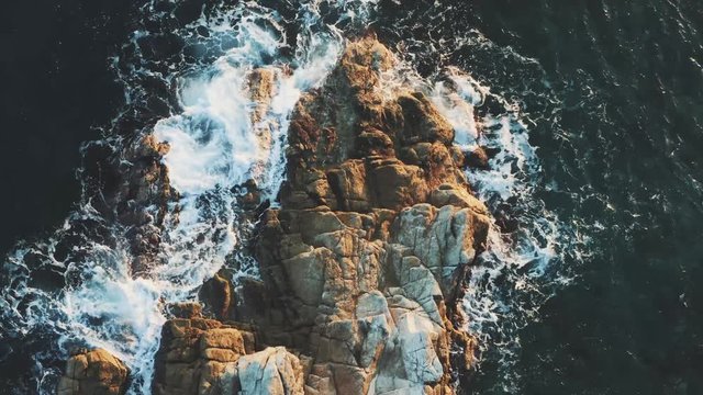 Top Aerial view of the ocean waves washing up on a cliff rock in Italy