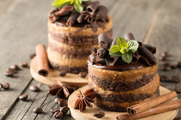 Dark chocolate cakes on black slattern board with mint, cinnamon, coffee beans on a wooden  background. Tasty dessert food concept.