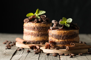 Dark chocolate cakes on black slattern board with mint, cinnamon, coffee beans on a wooden  background. Tasty dessert food concept.