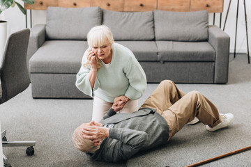 senior woman helping to husband who falled down on floor