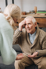 senior woman giving pills to old husband