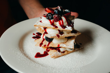 dessert on a white plate in the waiter's hand