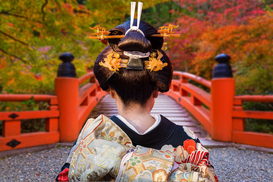 Woman in traditional kimono walking at the colorful maple trees in autumn, Japan