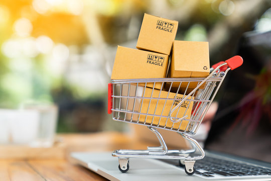 Package boxes in cart with laptop computer for online shopping concept
