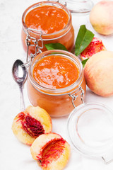 Homemade peach jam with organic fruit. Sweet preserves on a light background