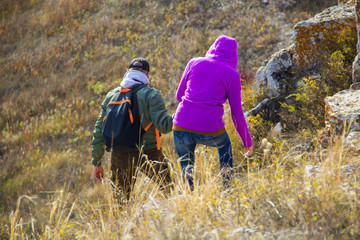 A man and a woman in warm clothes go down the path from the mountain while traveling..