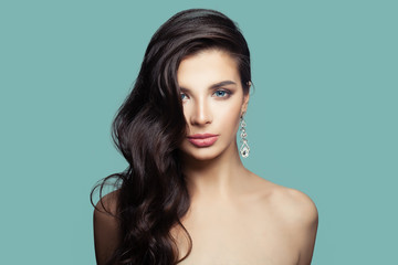 Young pretty woman with makeup and silver earrings with diamond on blue background