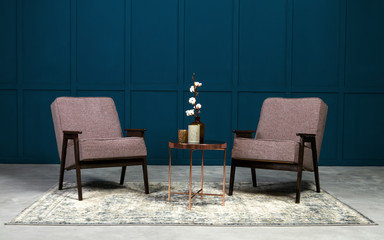 Fototapeta na wymiar Two gray armchair and copper coffee table and vases on it in blue room