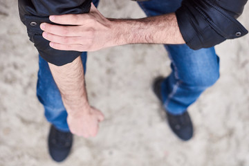 A man walks along the seashore, sits and thinks with his hands clasped. Closeup on a man hands and legs. Thinking about everything - Image