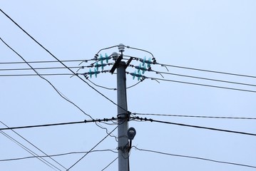 part one of a gray concrete pillar with black wires against the sky