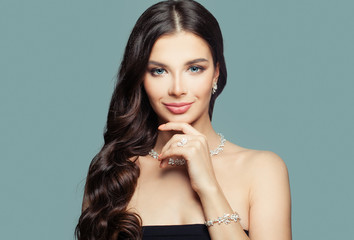 Happy girl with jewelry. Brunette woman with makeup and curly hairstyle and diamond necklace on...