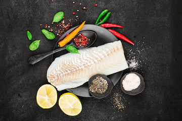 Cod fillets on a black ceramic plate for the preparation of a healthy dish with the addition of...