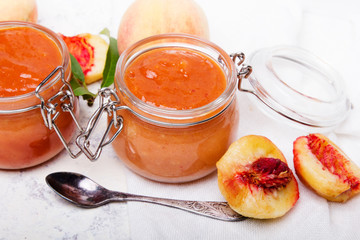 Homemade peach jam with organic fruit. Sweet preserves on a light background