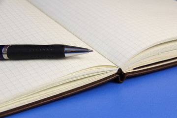 Open a blank white notebook and pen on the blue desk