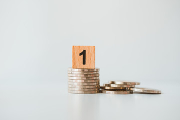 Closeup wooden block number one on stack coins using as business and finance concept