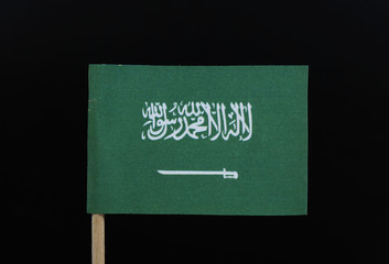 A official and unique flag of the Kingdom of Saudi Arabia on toothpick on black background. A green field with the Shahada or Muslim creed