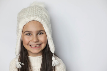 Happy smiling cute child girl in a white winter hat on white background. Positive emotiong.