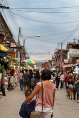 Fototapeta premium Mother and son on the street and blurry tourists at Walking Street Chiang Khan, Loei in Thailand.