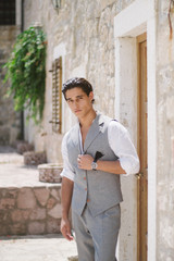 Attractive young fashion man in a suit walks around the old town.