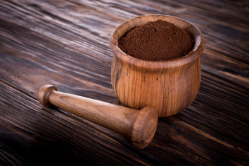 Mortar with ground coffee and pestle lie on a wooden board. Coffee in a mortar.