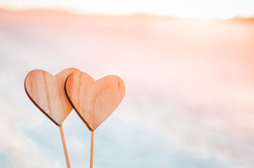 Fototapeta premium Two wooden hearts in orange sunset light