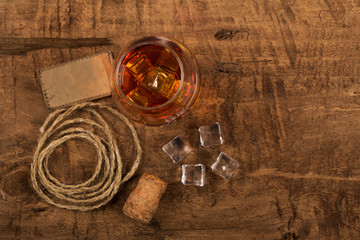 Whiskey with ice or brandy in a glass and a square carafe on an old wooden background. Whiskey with ice in a glass. Whiskey or cognac. Selective focus.