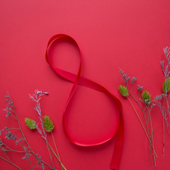 Satin red ribbon in the form of 8 on a red background