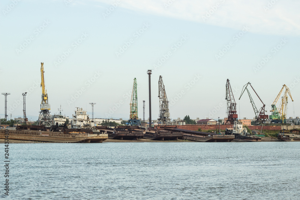 Wall mural a barge in the river port and working cranes on the city background