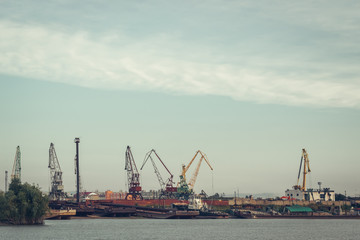 Naklejka premium A barge in the river port and working cranes on the city background 