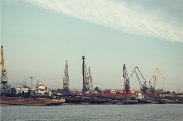 Fototapeta premium A barge in the river port and working cranes on the city background 