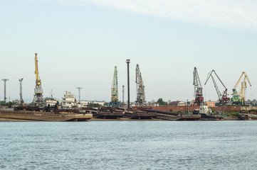 Fototapeta na wymiar A barge in the river port and working cranes on the city background 
