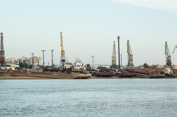 Fototapeta premium A barge in the river port and working cranes on the city background 
