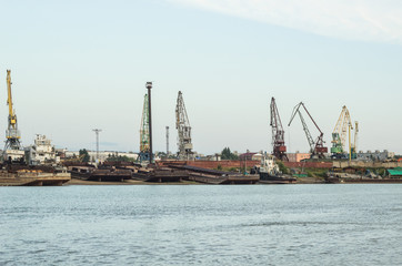 Fototapeta premium A barge in the river port and working cranes on the city background 