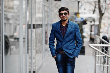 Young indian man on blue suit and sunglasses posed outdoor.