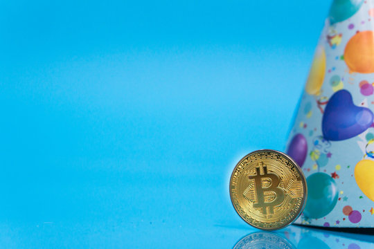 Bitcoin celebrating 10 year anniversary, coin with birthday hat behind it, with blue copy space