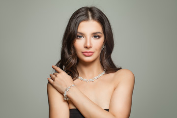 Glamorous jewelry model. Perfect brunette woman with makeup, long hair and diamond necklace and earrings portrait