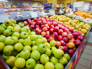 Green, red and yellow apples on the counter of the food supermarket.