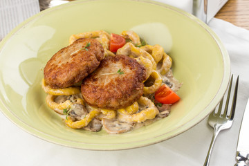 Meat patties with mushrooms and spaghetti on white textile table