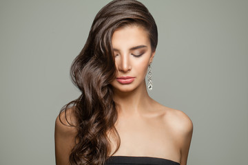 Fashion portrait of brunette woman with long curly hair, makeup and diamond jewelry earrings
