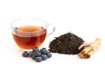 Cup of tea, stacked dried tea leaves, cinnamon, cranberries, isolated on white background